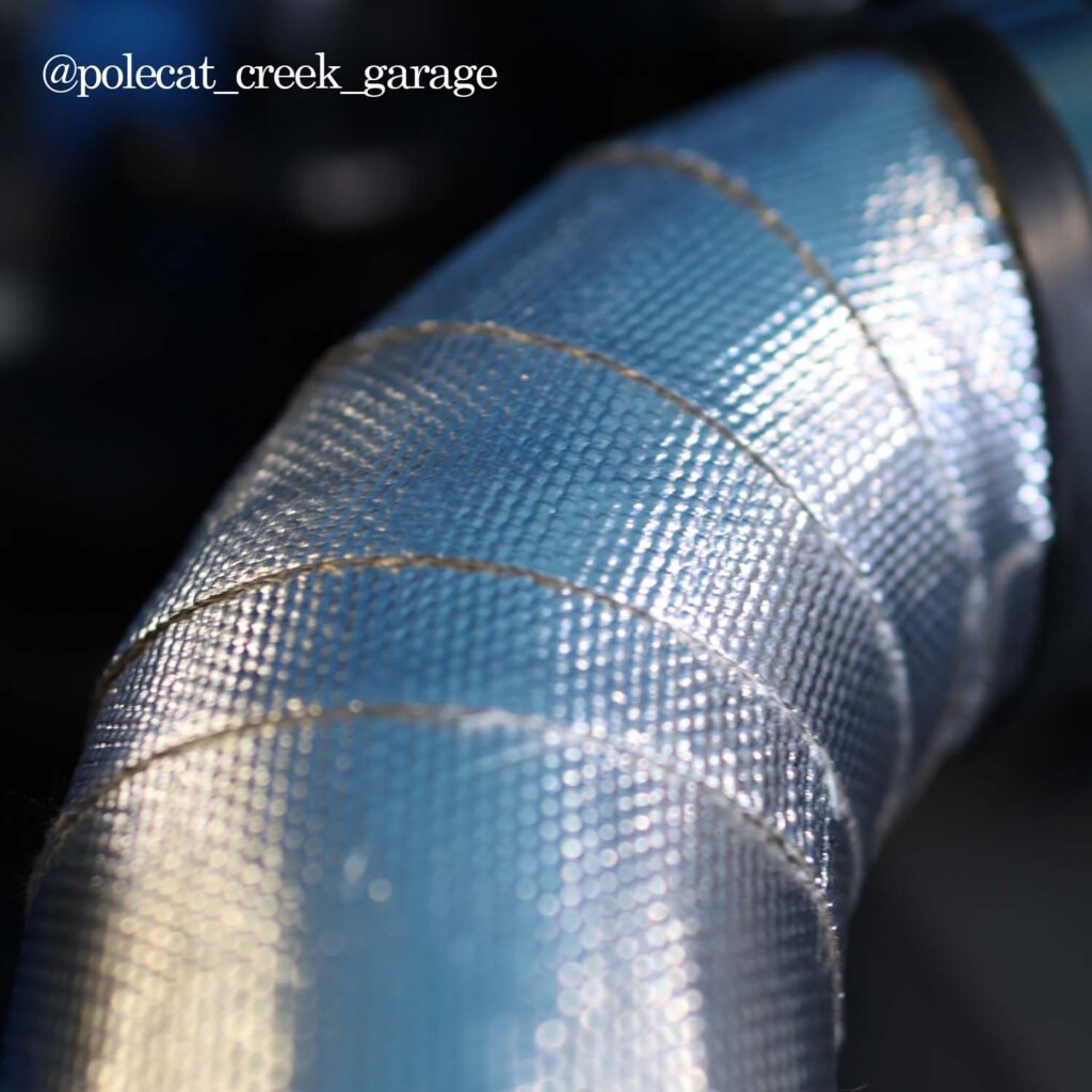 Heatshield Products Thermaflect Tape wrapped tightly on intake tube, highlighting thermal barrier texture.