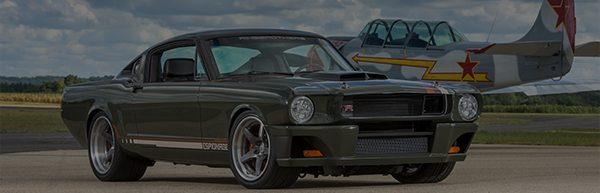 Custom Ringbrothers Mustang parked near a vintage fighter plane on an airstrip