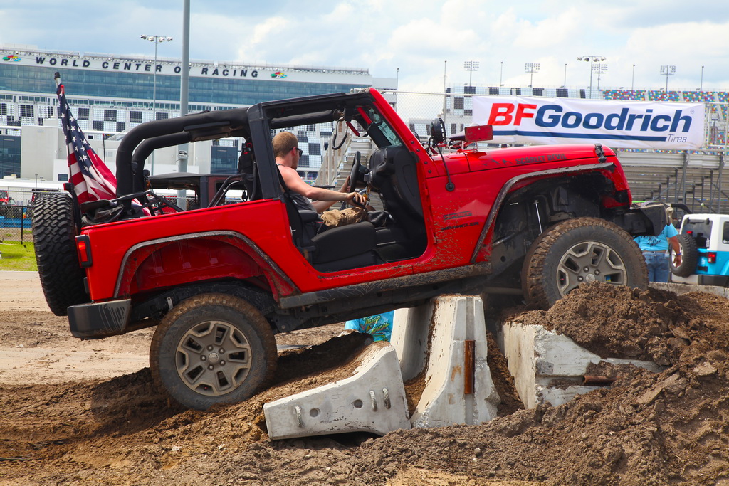 Red Jeep Drives Over Mound of Dirt