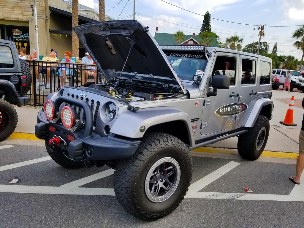 Grey Jeep With the Hood Popped Sits at Car Show