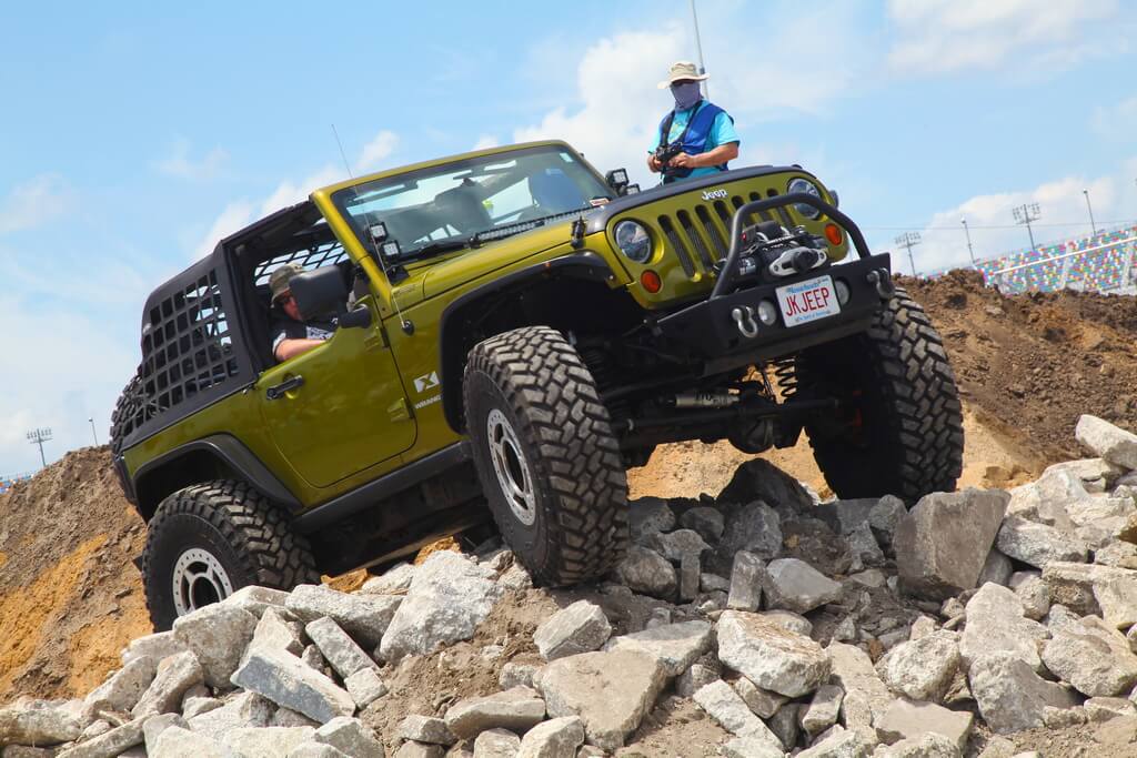 Olive Green Jeeps Drives Over Mound of Rocks