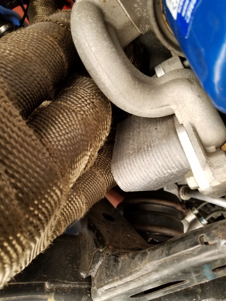 Exhaust headers with exhaust wrap installed running close to an LS series V8 engine oil cooler