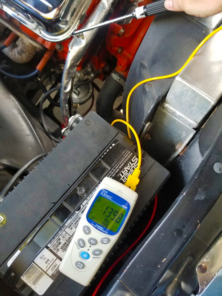 A thermometer measures the temperature of a car engine installed without fuel line protective sleeves.