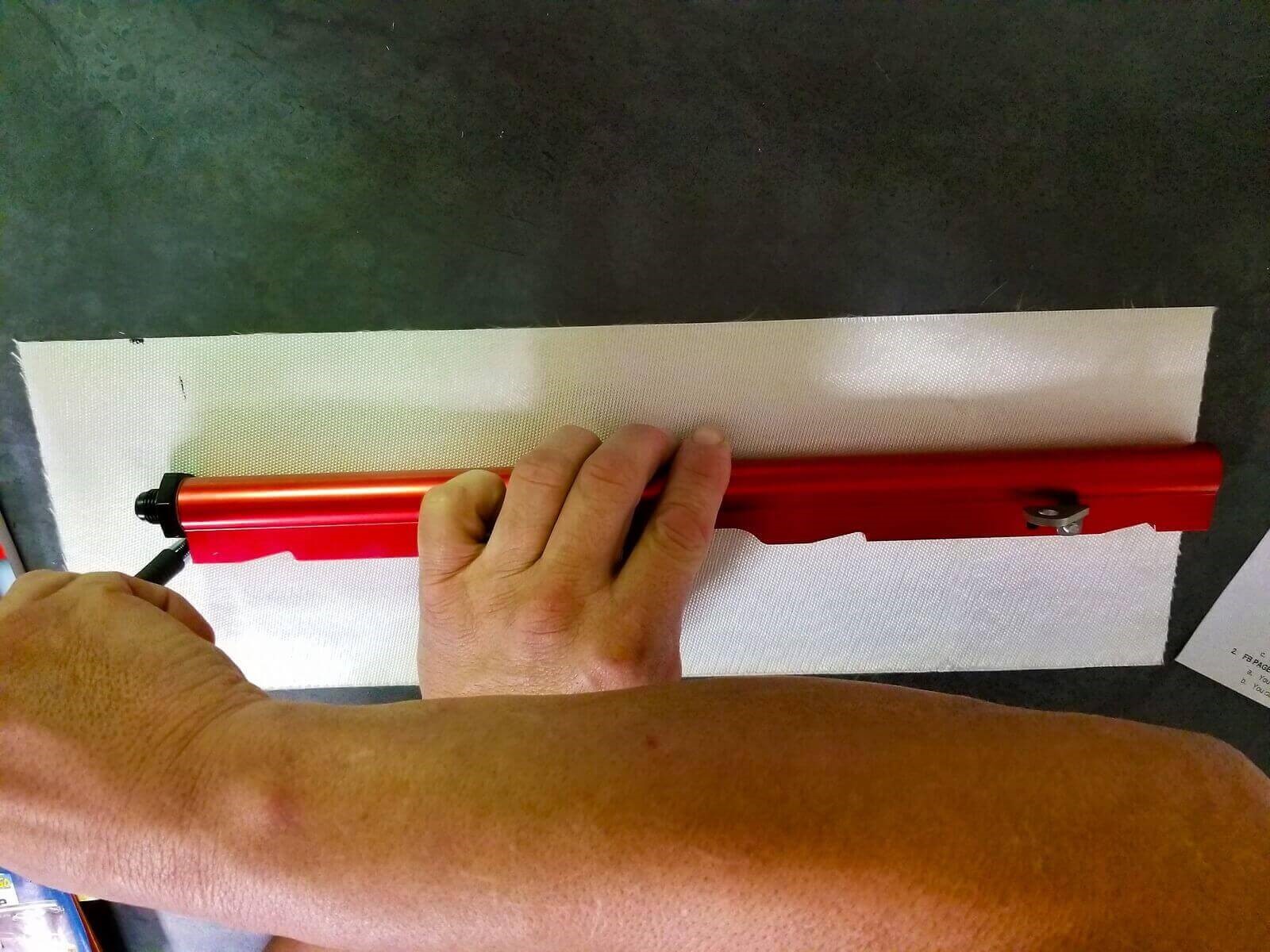 A man measures fuel line insulation against a fuel rail