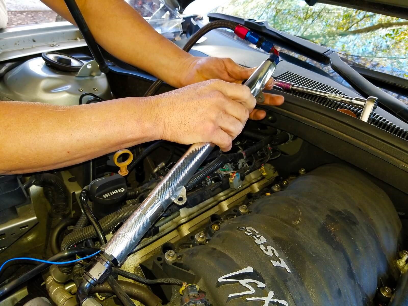 A man secures fuel line insulation against a fuel rail with heat tape.