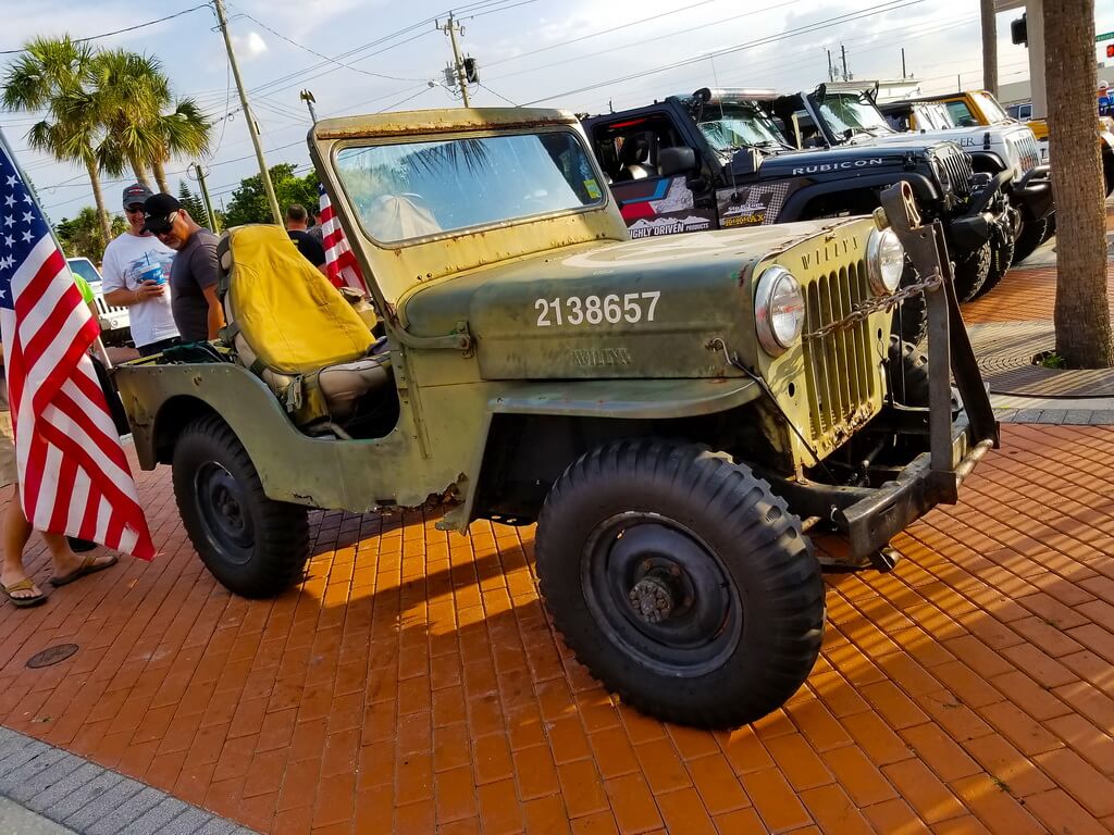 Rusted Green Jeep Sits in Parking Lot at Car Show