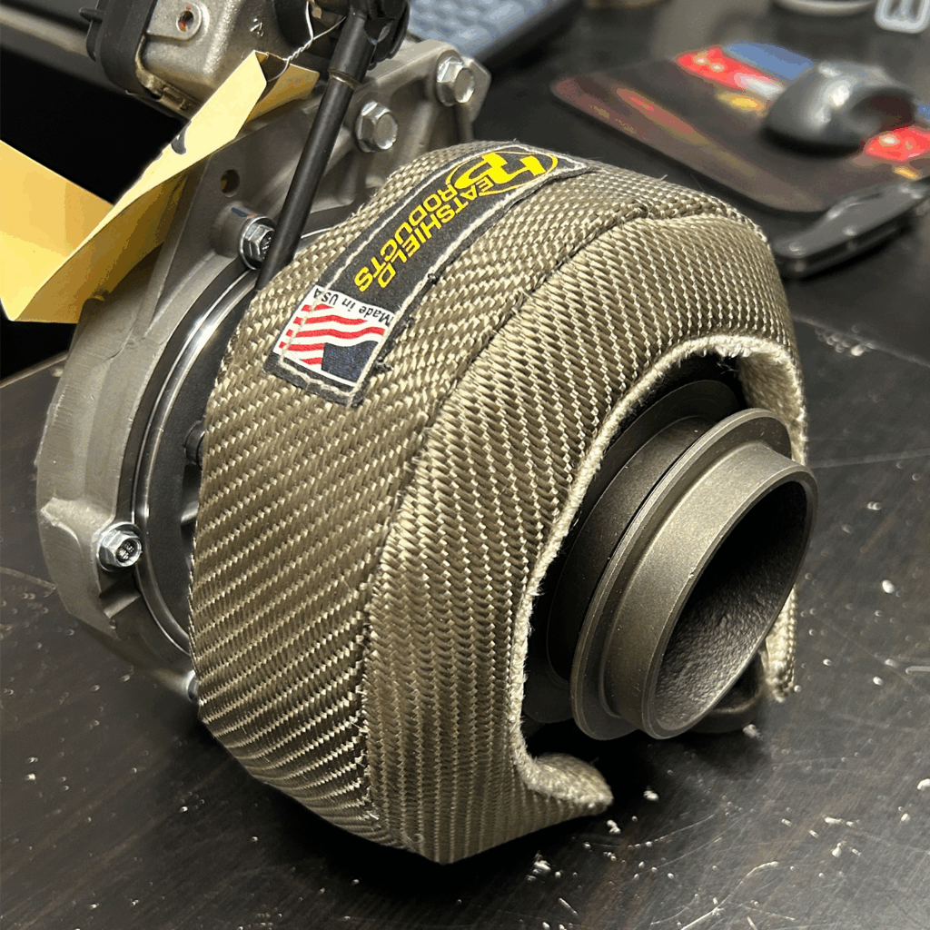 Custom-fabricated turbo heat shield on Mercedes turbocharger highlighting precision fitment, fasteners, and heat-resistant materials for racing performance.