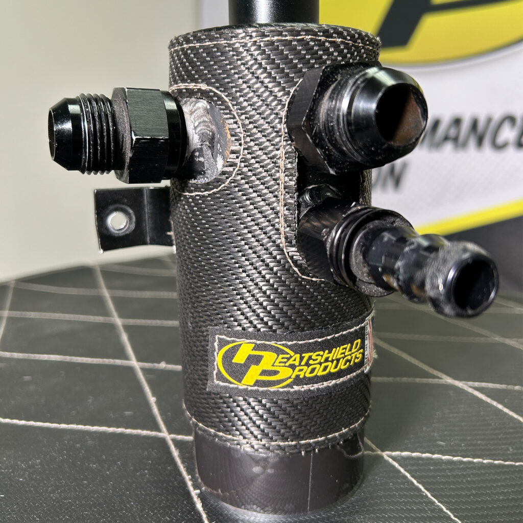 High-performance oil catch can with custom Heatshield Products insulation, featuring precision-stitched carbon fiber material for maximum heat protection.