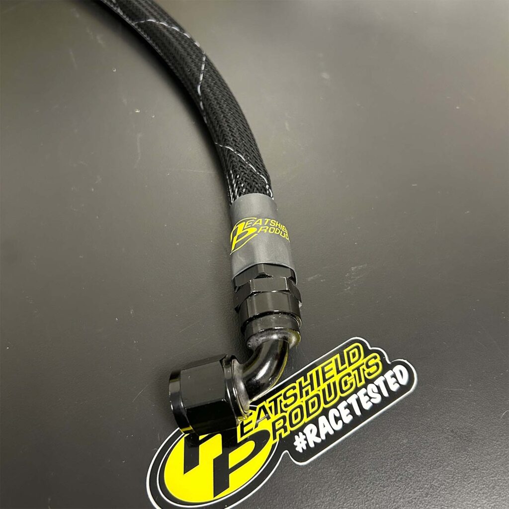 Heatshield Products abrasion-resistant hose sleeve installed on braided AN line with black 90-degree fitting